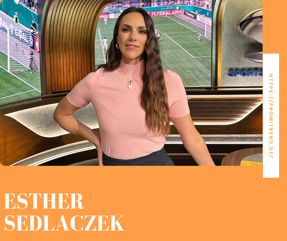 Eine Frau in einem rosa Oberteil steht in einem Fernsehstudio mit einem Fußballspiel im Hintergrund. Der Name "Esther Sedlaczek" ist unten im Bild zu sehen.