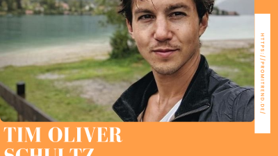 Ein Mann steht vor einem See mit Bergen im Hintergrund. Sein Gesicht ist unscharf gemacht. Auf dem Bild steht "TIM OLIVER SCHULTZ FREUNDIN" und die URL "HTTPS://PROMITREND.DE/".