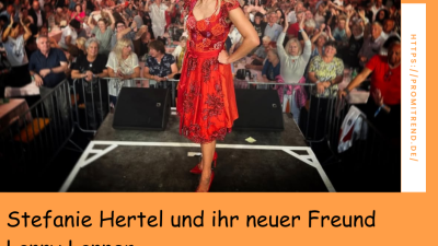 Eine Frau in einem roten Kleid steht auf einer Bühne vor einem großen Publikum.